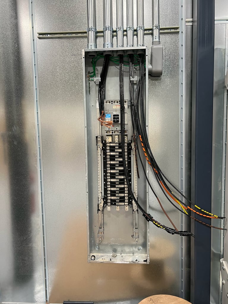 Electrical panel interior showing circuit breakers, wiring, and terminal connections mounted on metal rails