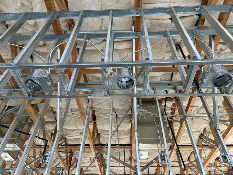 Metal framing with HVAC ducts and wiring installed in building under construction showing exposed wooden beams and insulation