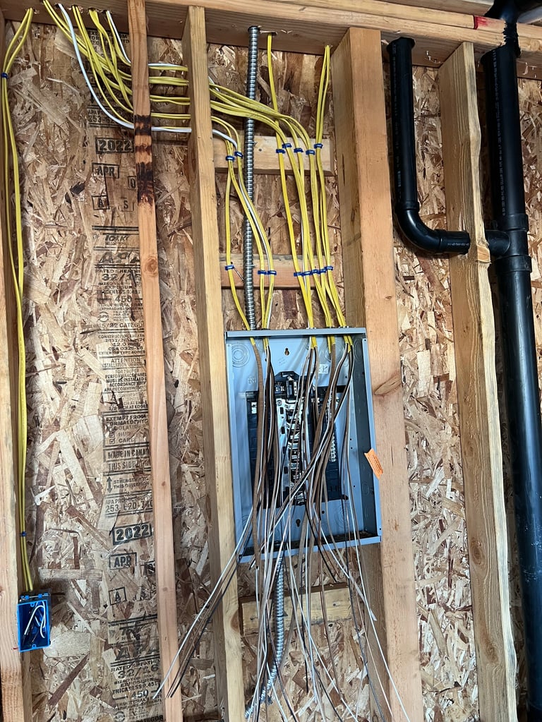 Electrical wiring installation in wall framing with yellow and black cables running through wooden studs and blue conduit box