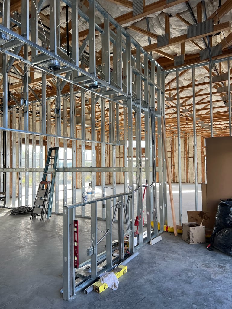 Interior of residential construction site with metal stud framing and wooden roof trusses during building frame stage