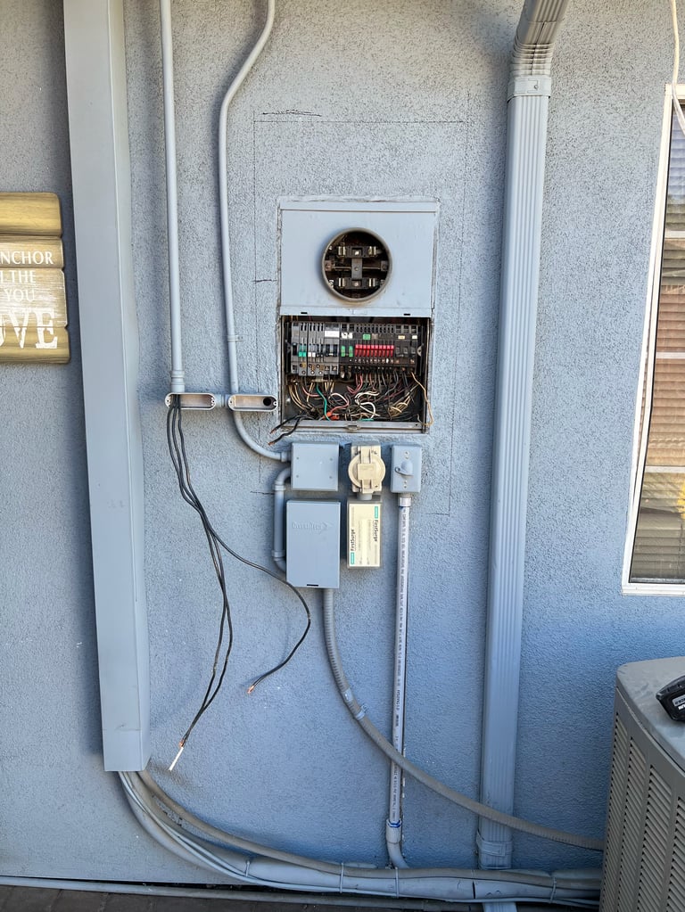 Electrical meter and circuit breaker box mounted on exterior wall with gray conduit and power cables