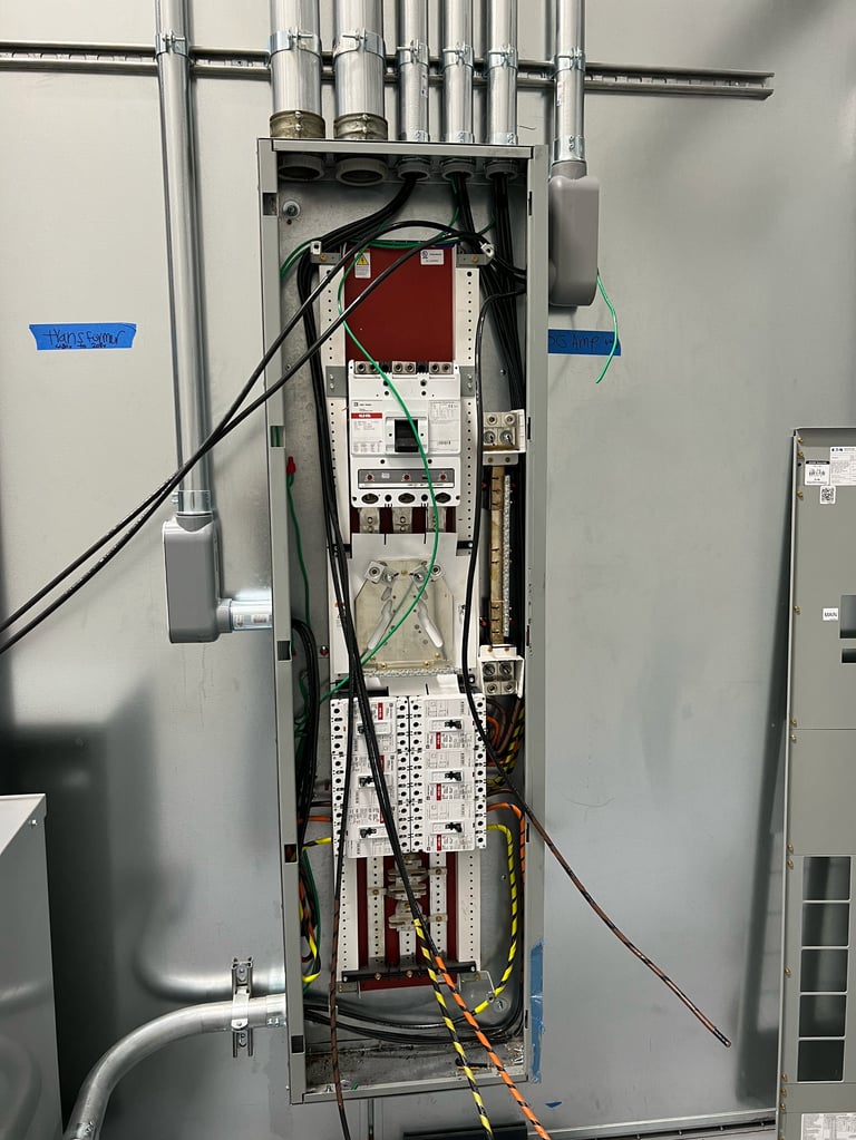 Open electrical panel showing circuit boards, wiring, and components with metal conduit connections at top