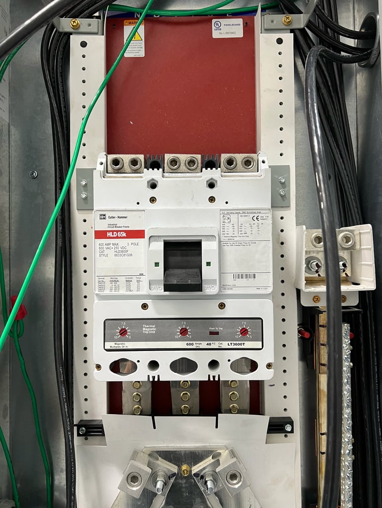 Industrial electrical circuit breaker panel with red disconnect switch, terminal blocks, and color-coded wiring mounted on metal frame