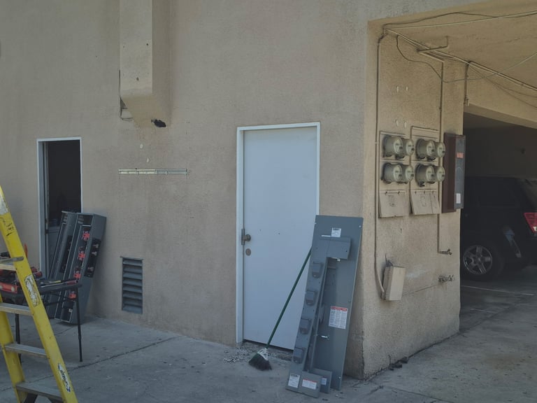 Industrial garage interior with a light blue door, stacked materials, yellow ladder, and beige electrical panels on the wall