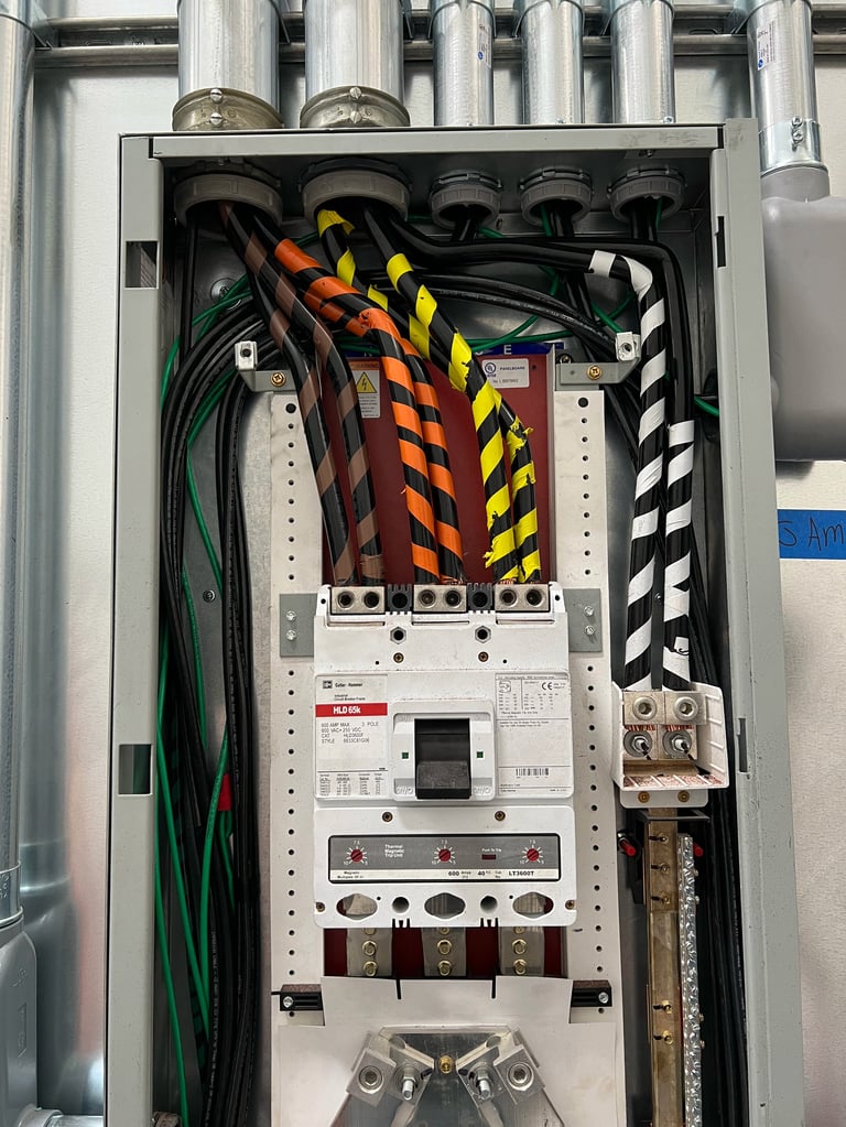Electrical panel with organized colored cable management, circuit breakers, and wiring mounted in industrial enclosure